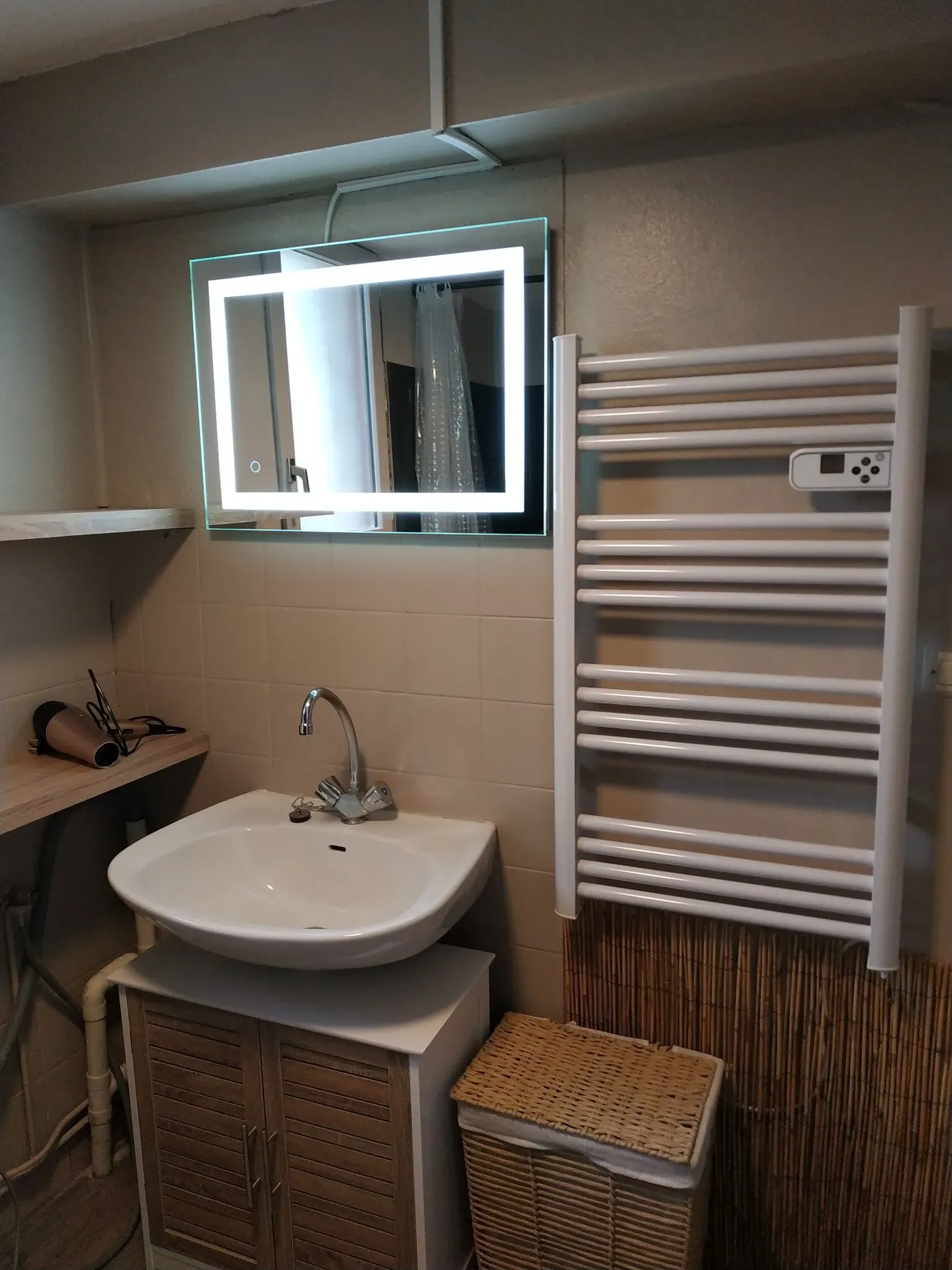 Salle de bain avec lavabo, miroir éclairé et sèche-serviettes