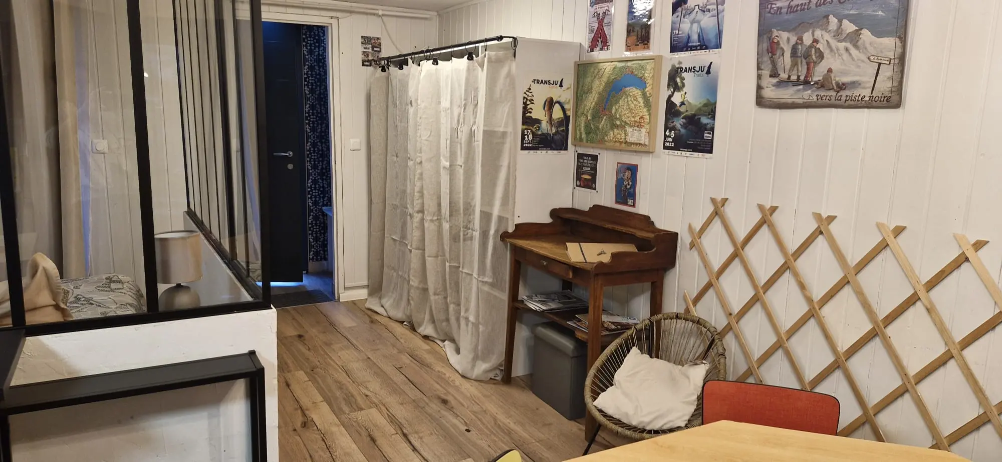 Coin détente avec bureau en bois, fauteuil en rotin et affiches de montagne