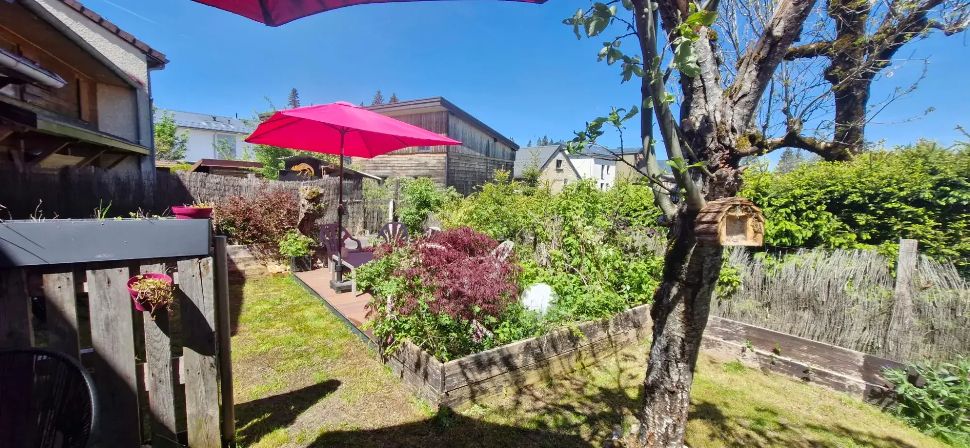 Jardin avec massif fleuri et terrasse en bois