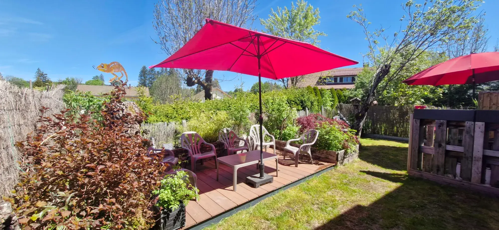 Terrasse en bois avec salon de jardin sous un parasol rouge