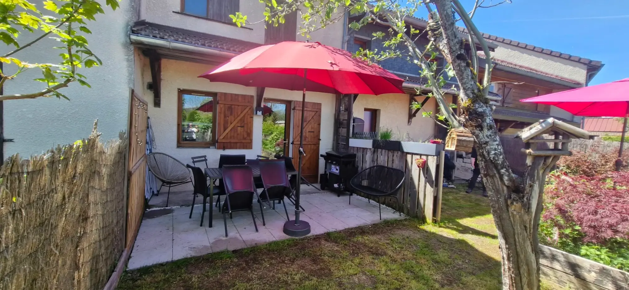 Terrasse dallée devant la maison, avec table et parasol